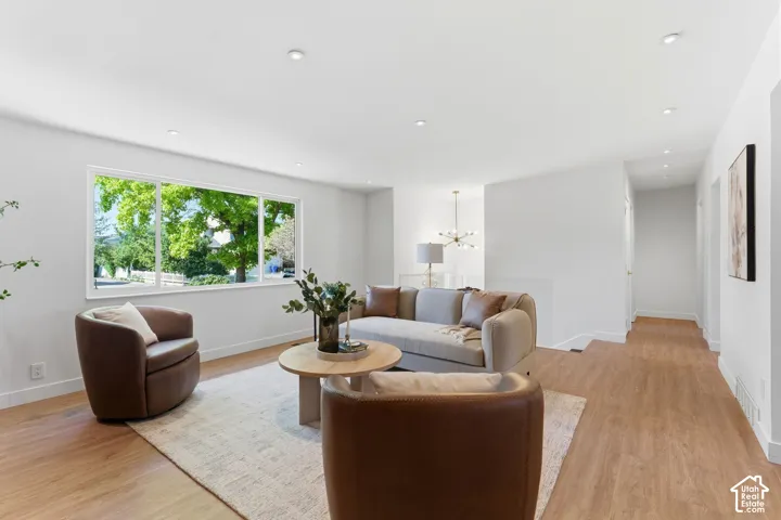 Expansive windows, wood-finish flooring, recessed lighting, white trim, and a contemporary chandelier