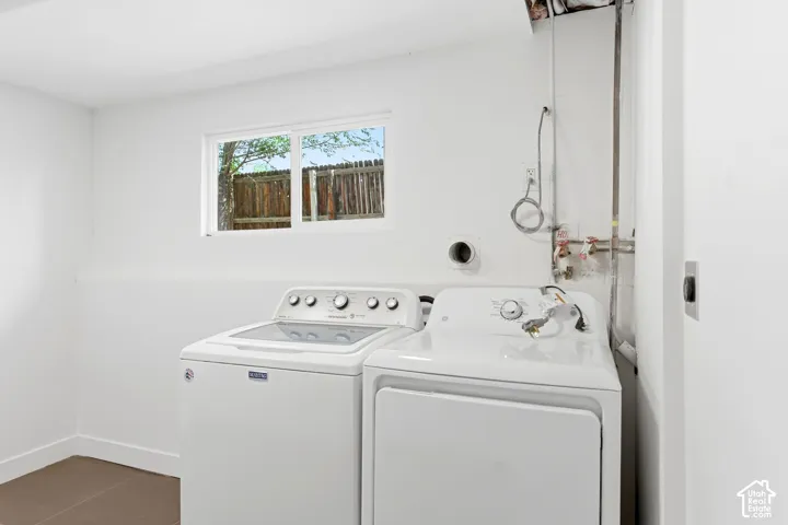 Laundry area with a window, white walls, and dark-toned flooring