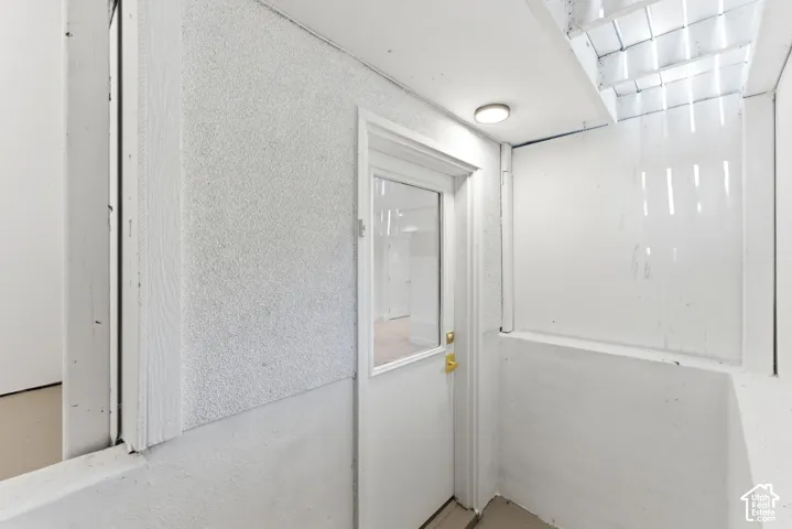 Recessed ceiling light fixture, white door with clear glass panel, and textured wall finish