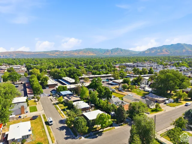 Aerial view showcasing this residential property situated within an established neighborhood featuring mature tree canopy, manicured landscaping, and mountain backdrop