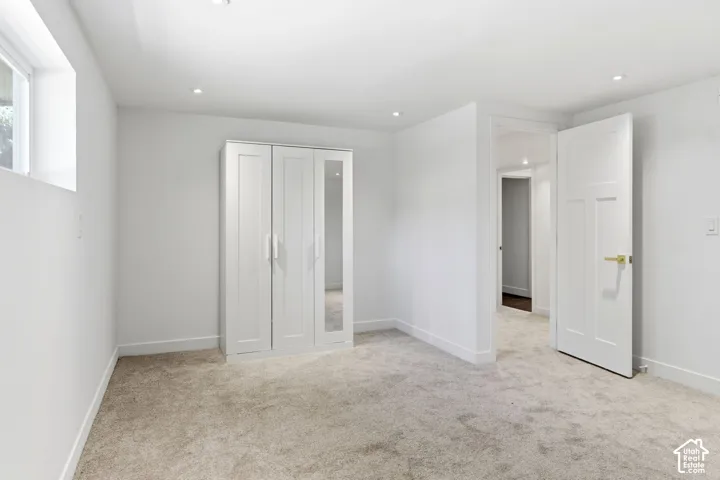 Neutral carpet flooring, recessed lighting, white walls, white trim, and a window