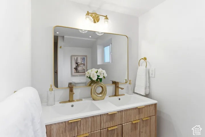 Dual vanity with white undermount sinks, wood-finish cabinetry, and gold-finish hardware
