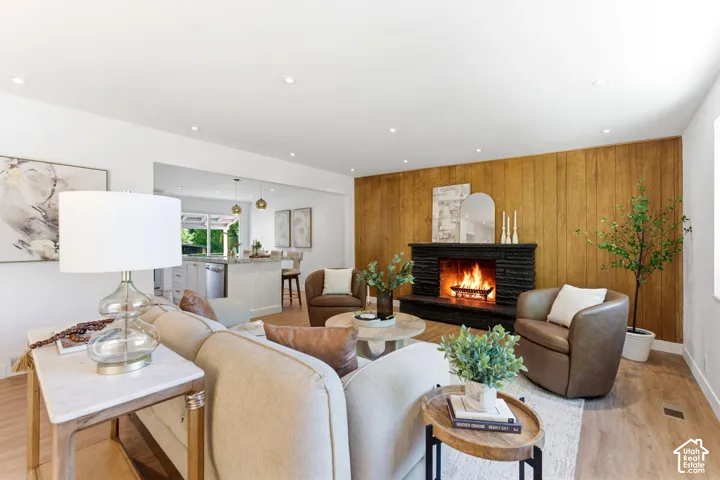 Open-concept living space featuring wood-finish flooring, recessed lighting, and a stone-clad fireplace