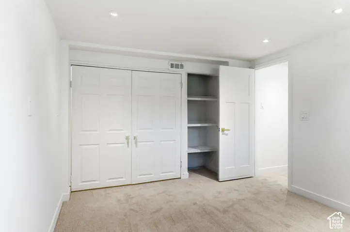 Recessed lighting, light-toned carpeting, white walls, and built-in shelving
