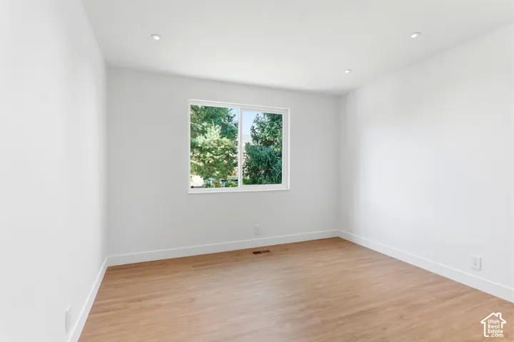 Recessed lighting, wood-finish flooring, white walls, and a large window