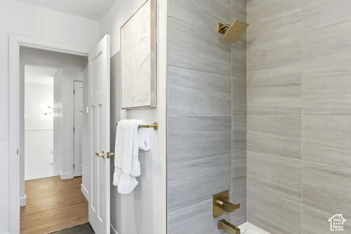 Shower with large format grey-toned tile surround, gold-finish fixtures, and a rain shower head