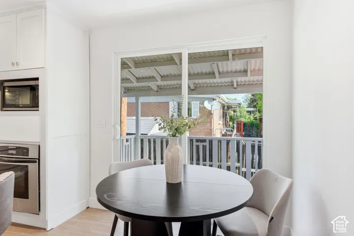 Built-in stainless steel microwave and oven, white cabinetry, wood-finish flooring, and a sliding glass door to an outdoor area