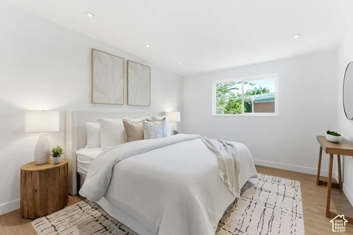 Recessed ceiling lighting, wood-finish flooring, white walls, and a window with a white frame