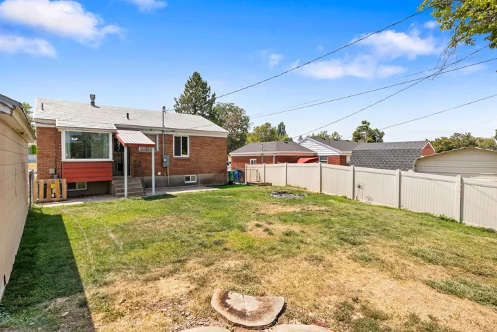 Expansive backyard with a level lawn area, brick exterior, and a white privacy fence