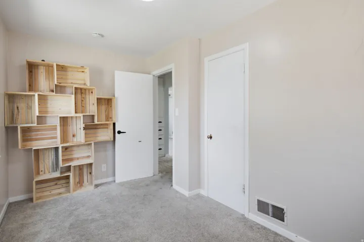 Wall-mounted wood storage boxes, neutral wall color, and carpeted flooring