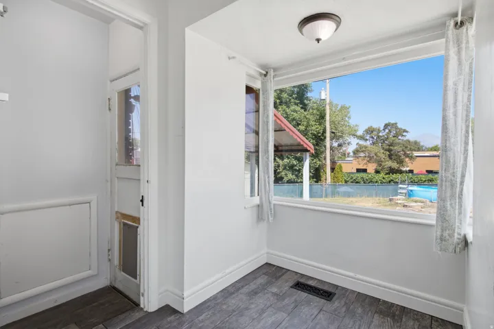 Wood-finish flooring, white trim, and a window with a ceiling-mounted light fixture