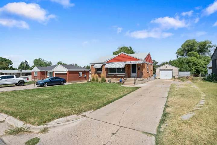 Brick exterior with a red gable roof, front entrance awning, and concrete driveway leading to a detached garage