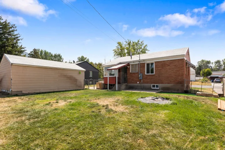 Expansive yard with a detached garage, brick exterior, and partial fencing