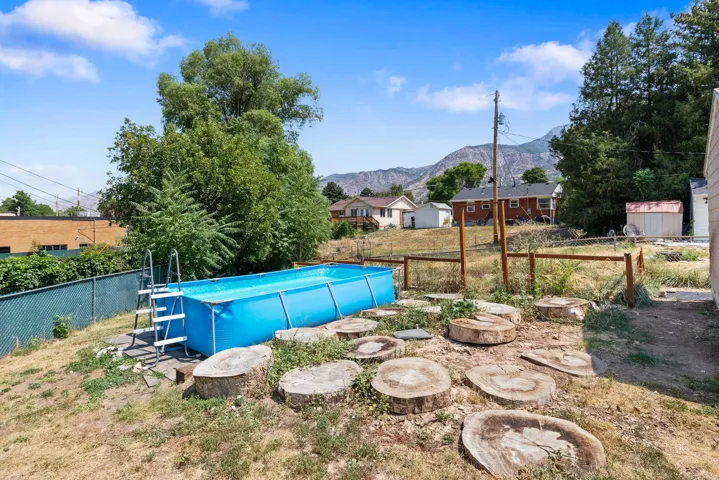 Expansive yard featuring a large above-ground pool, mature trees, and natural wood steps