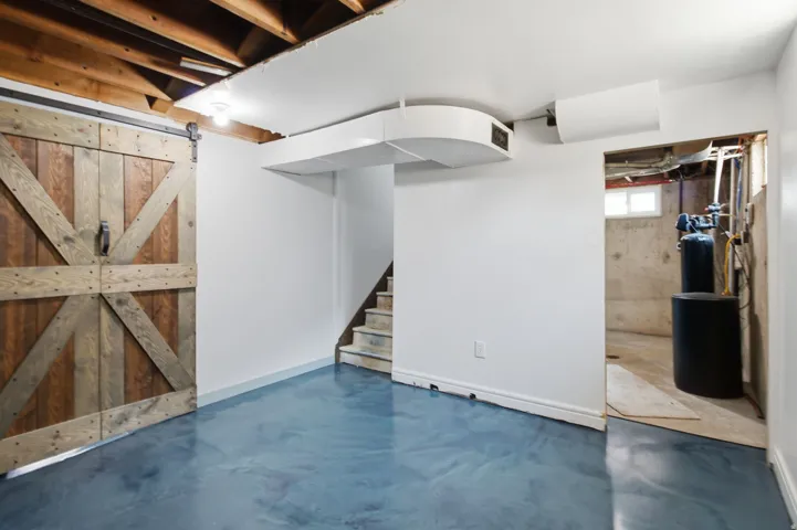 Exposed wood ceiling joists, wood-finish barn door, concrete flooring, interior staircase, and exposed ductwork