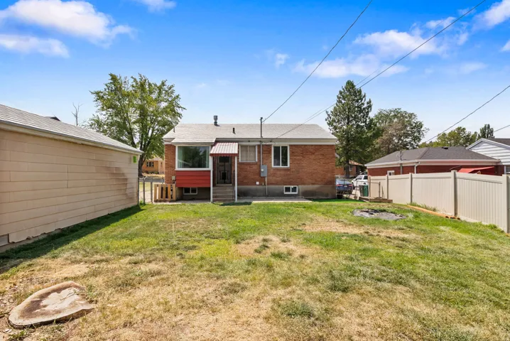 Brick exterior home with a partial vinyl privacy fence and a detached garage featuring siding
