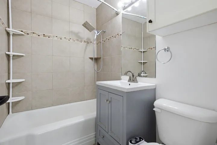Tile-surround bathtub with decorative accent band and modern showerhead