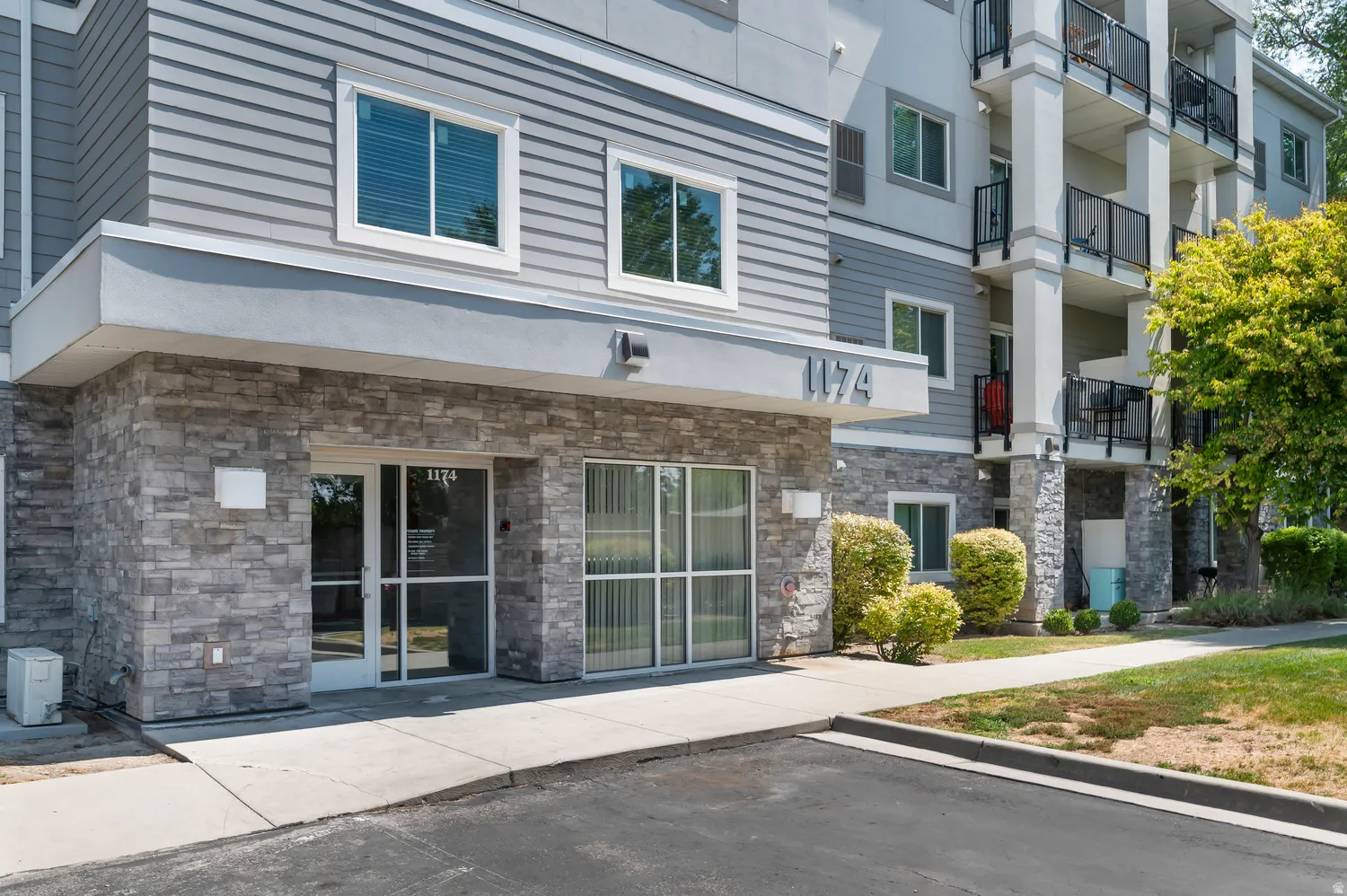 Building exterior featuring stone veneer, horizontal siding, multiple windows, and a paved entry