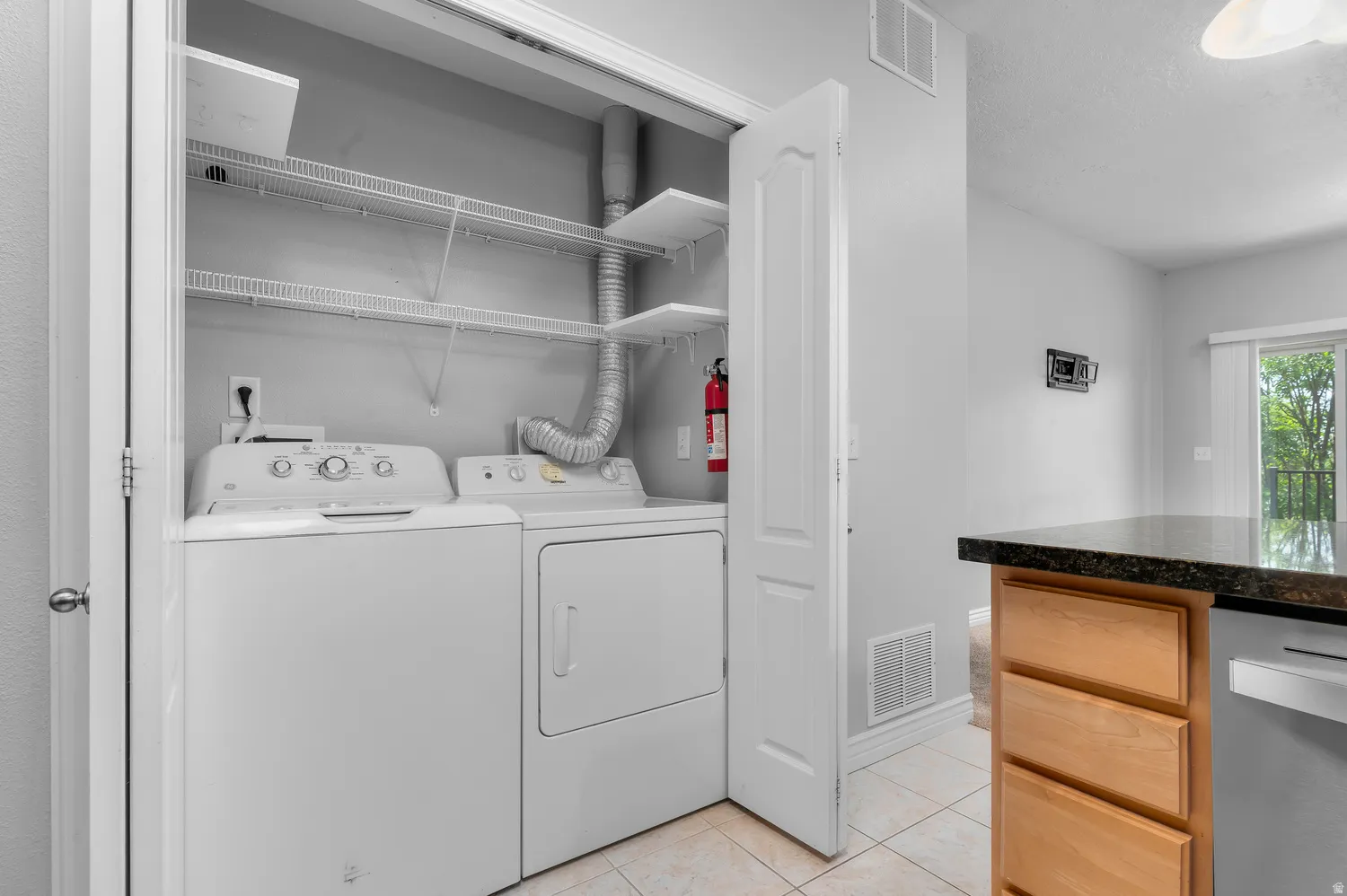 Dedicated laundry closet with washer and dryer, wire shelving, and tile flooring