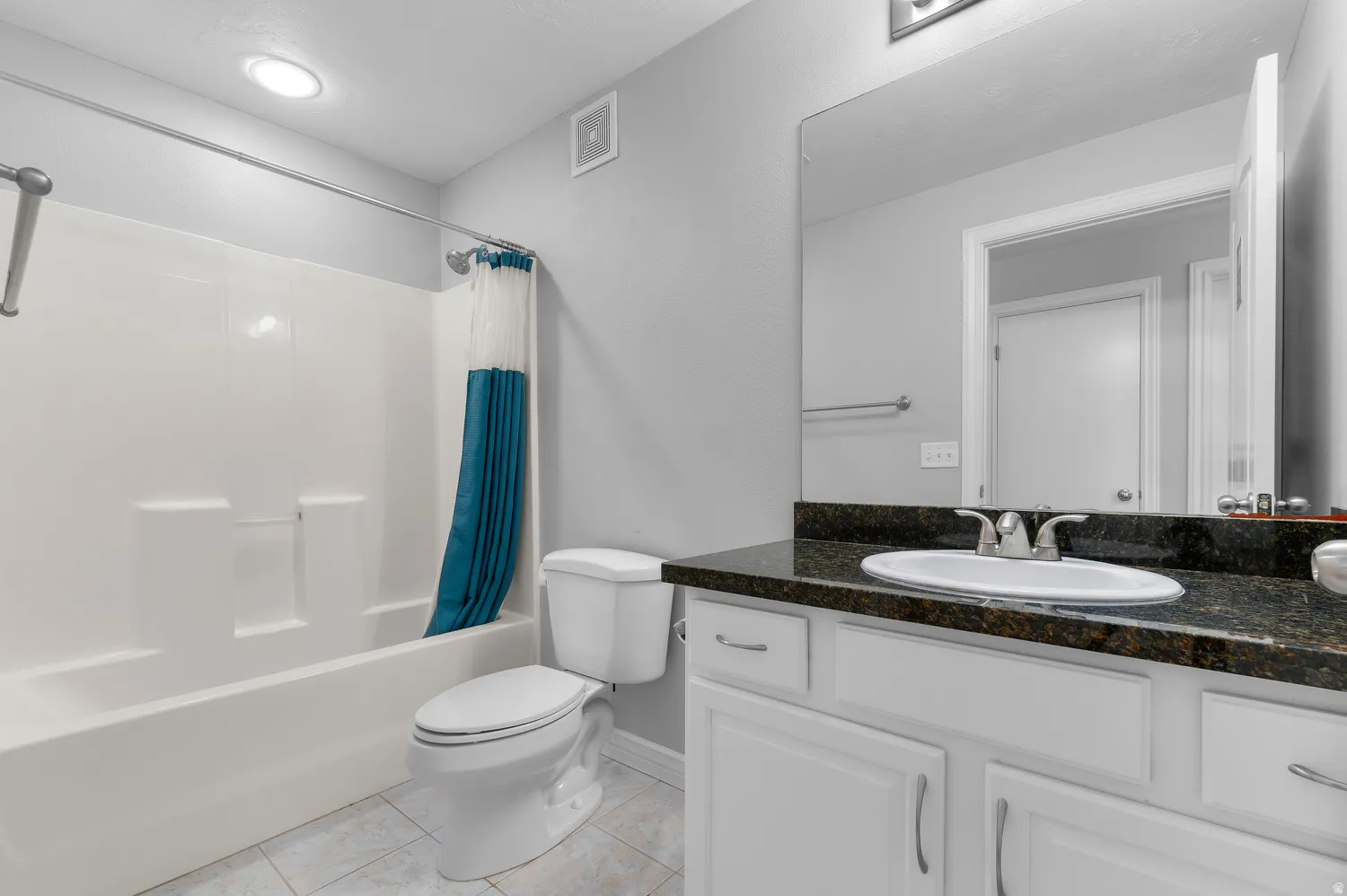 White vanity with dark stone-finish countertop and integrated sink