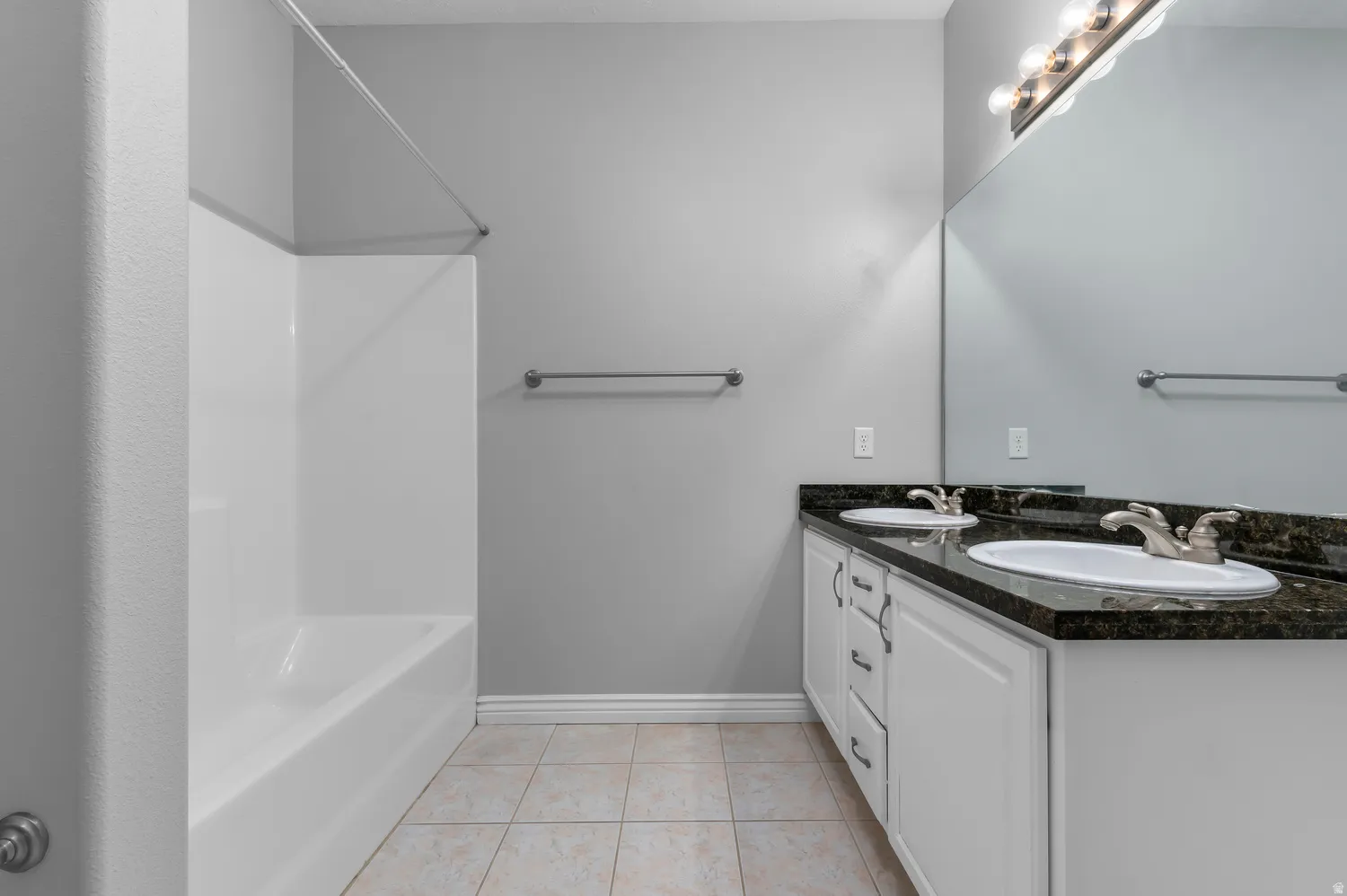 Dual vanity with white cabinetry, dark stone countertop, and brushed nickel fixtures