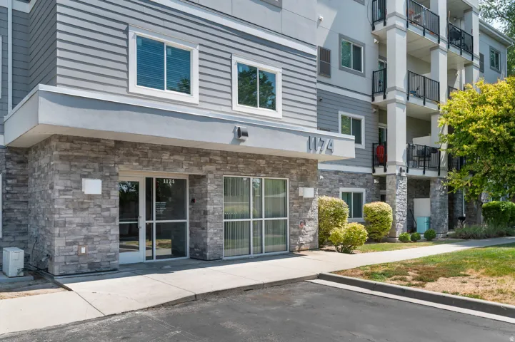 Building exterior featuring stone veneer, horizontal siding, multiple windows, and a paved entry