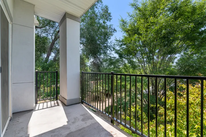Patio featuring a concrete surface, black metal railings, and an exterior door with a screen