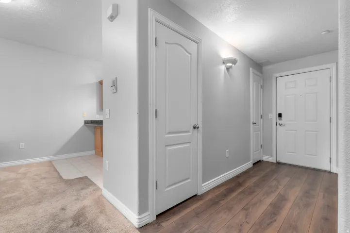 Wood-finish flooring, white paneled doors, and a wall-mounted sconce