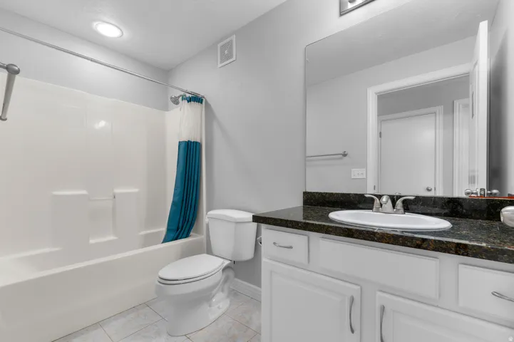 White vanity with dark stone-finish countertop and integrated sink