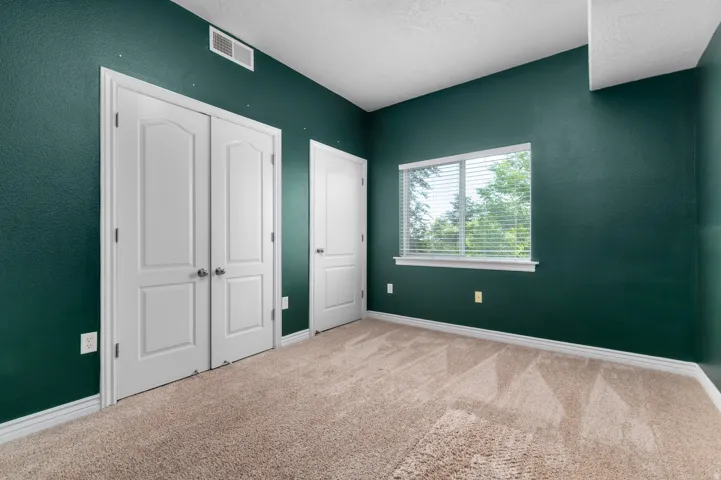 Wall-to-wall carpet flooring, double panel closet doors, single window with blinds, and white trim