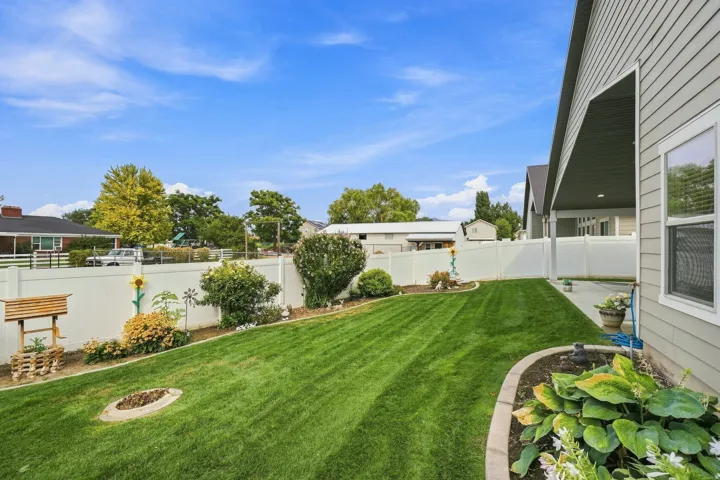 Expansive backyard featuring a manicured lawn, established perimeter landscaping, and a fire pit