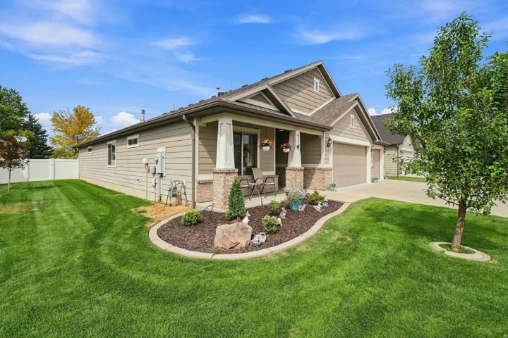 Covered front porch with substantial columns, stone veneer accents, and an attached two-car garage
