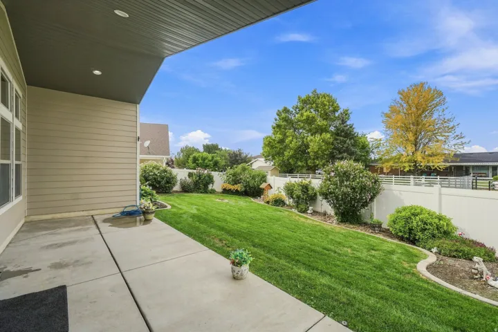 Covered concrete patio with recessed lighting, siding exterior, and a manicured lawn with established landscaping