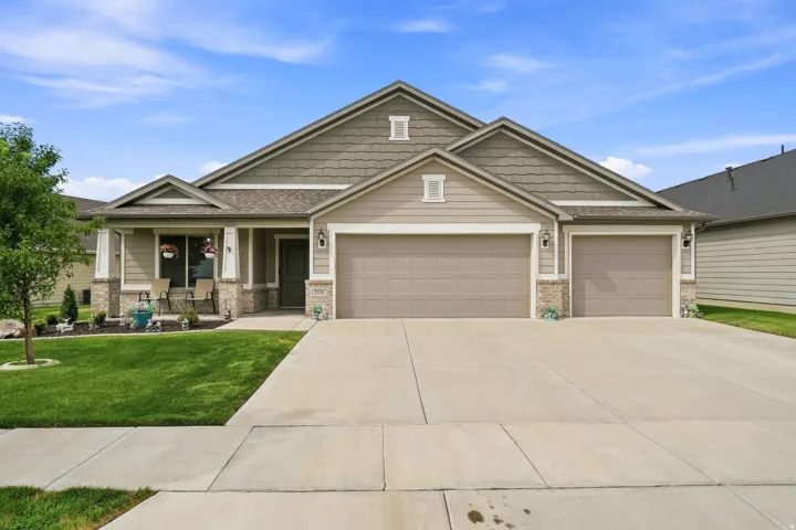 Siding exterior with stone accents, a covered front porch, and an attached two-car garage