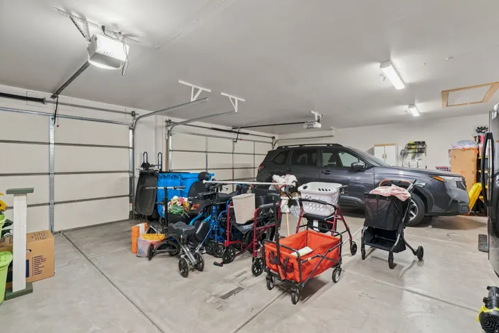 Attached two-car garage featuring a concrete floor and overhead lighting