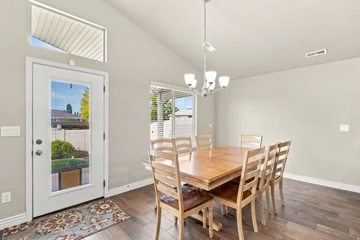 Vaulted ceiling, wood-finish flooring, full-light exterior door, transom window, and a chandelier with frosted glass shades
