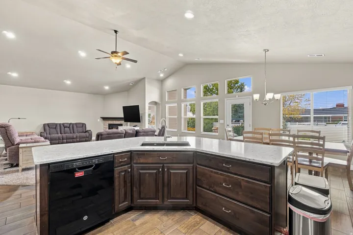 Kitchen island with light-colored countertop, dark wood-finish cabinetry, and an integrated dishwasher