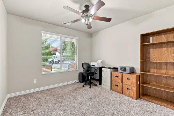 Carpeted room featuring a ceiling fan with integrated lighting, a window with horizontal blinds, and neutral wall paint