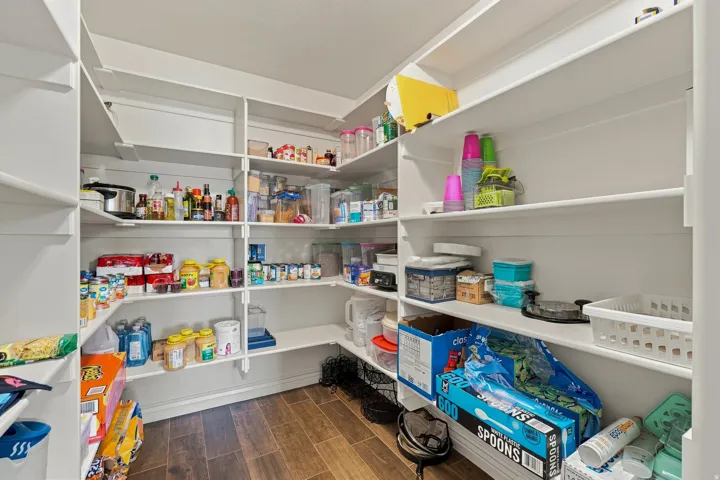 Spacious pantry featuring extensive built-in shelving and wood-finish flooring