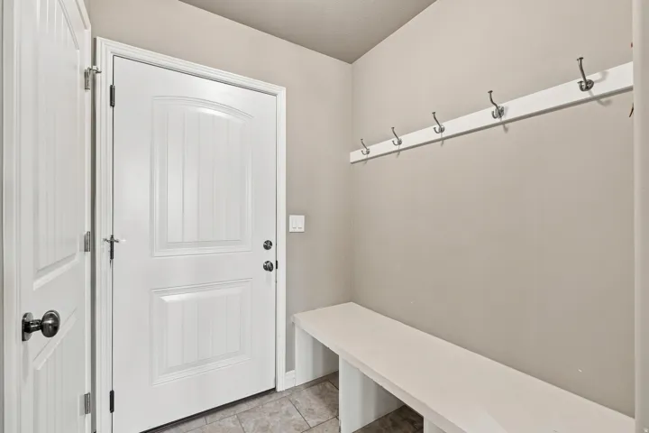 White paneled doors with black hardware, built-in bench, and coat hooks