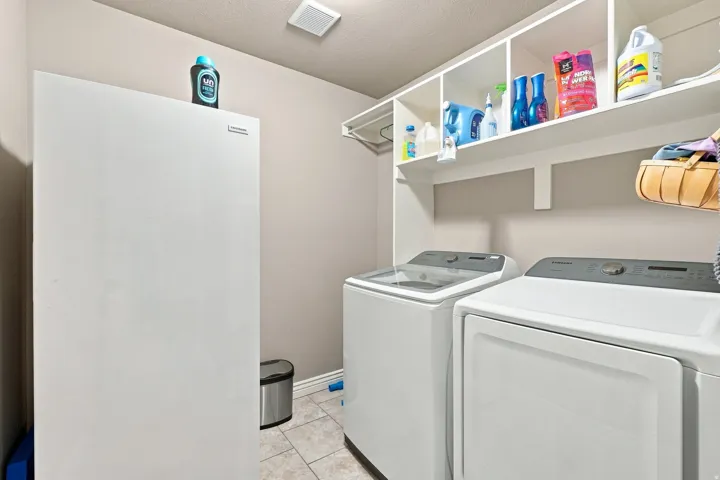 Integrated white shelving, laundry appliances, and tile flooring