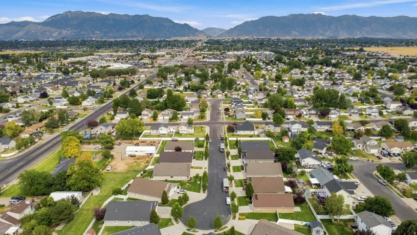 Residential neighborhood with tree-lined streets, manicured lawns, and distant mountain scenery