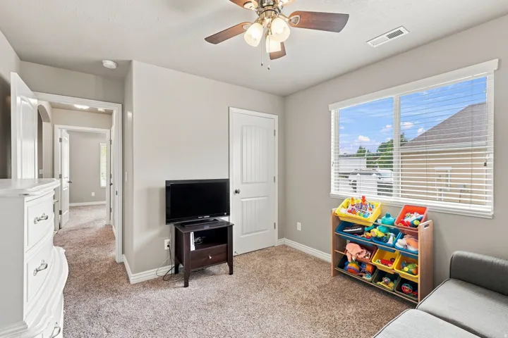 Carpeted room with a ceiling fan, window with blinds, and white paneled doors