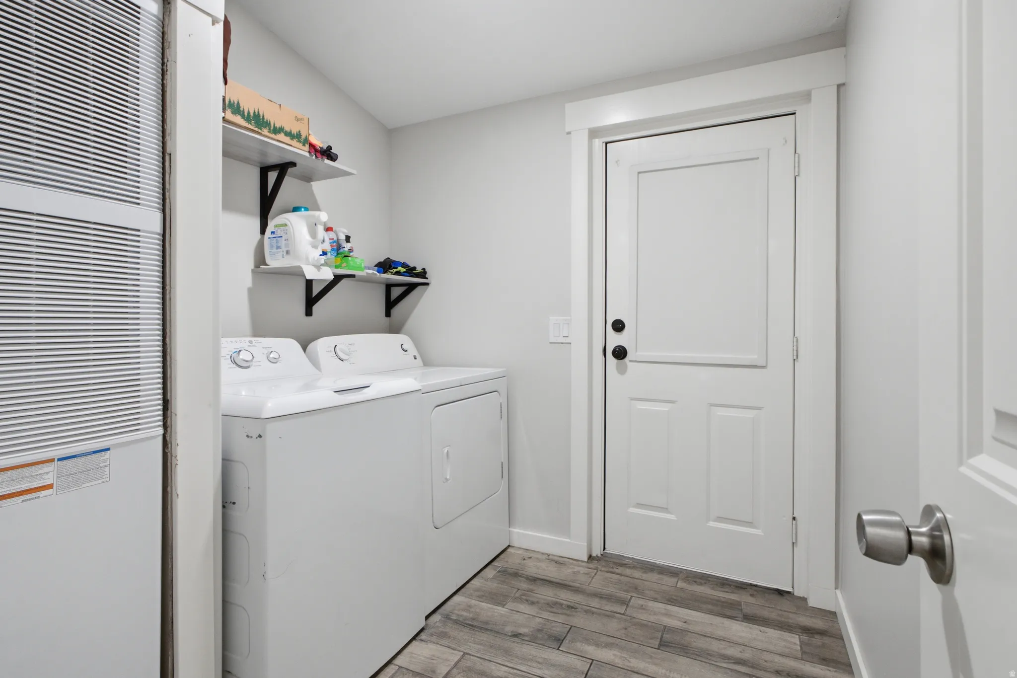 Wood-finish flooring, white walls, and a white paneled door with black hardware
