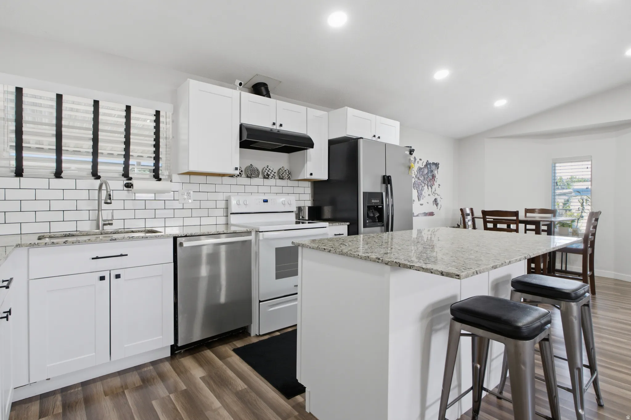 White cabinetry with black hardware, stainless steel appliances, and a subway tile backsplash