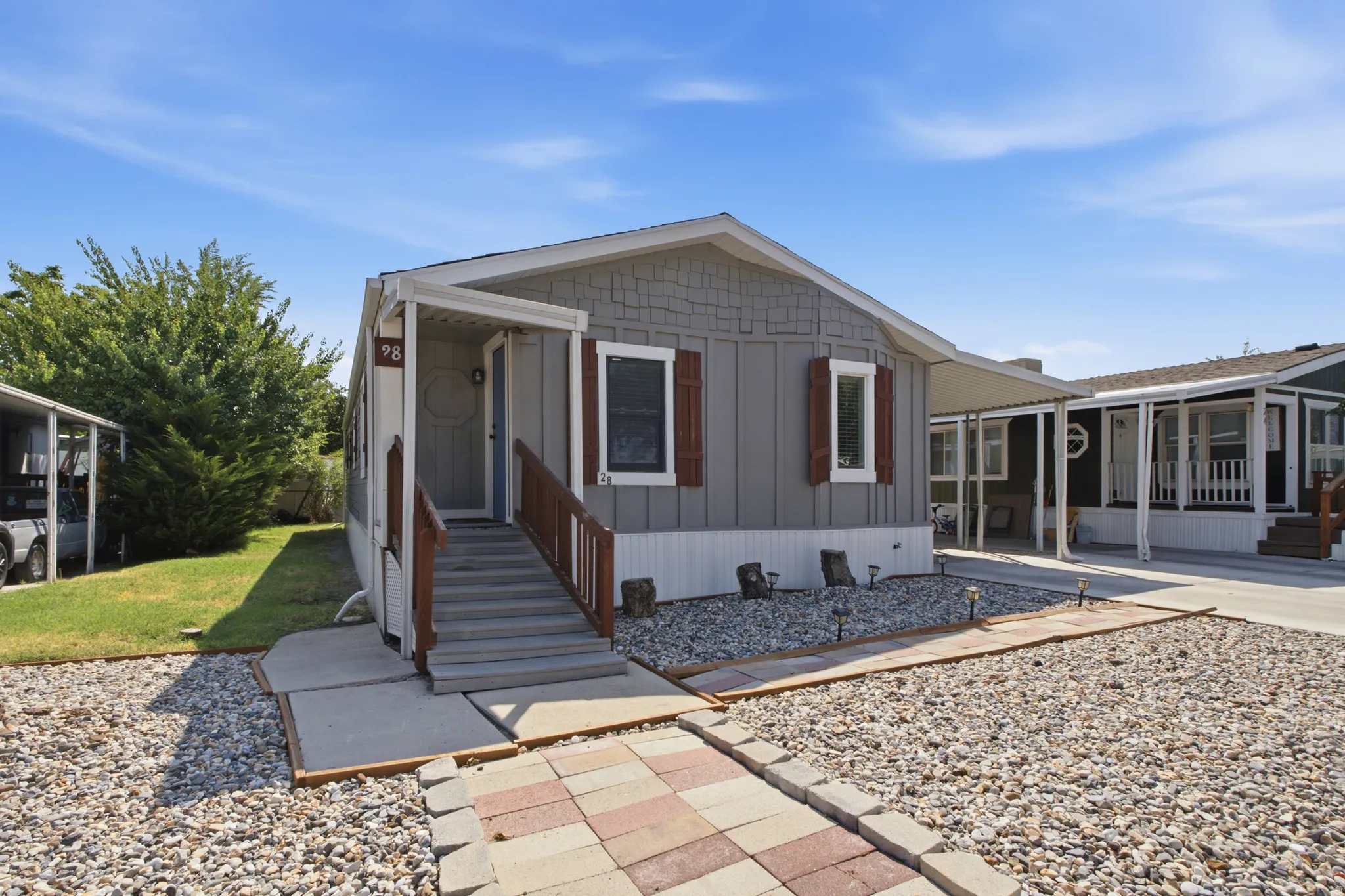 Grey exterior siding with decorative wood shutters, covered entry, and a paved walkway