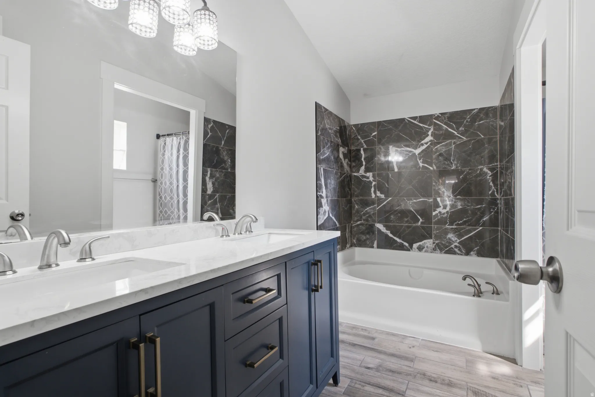Dual vanity with white countertop, dark blue cabinetry, and satin nickel hardware