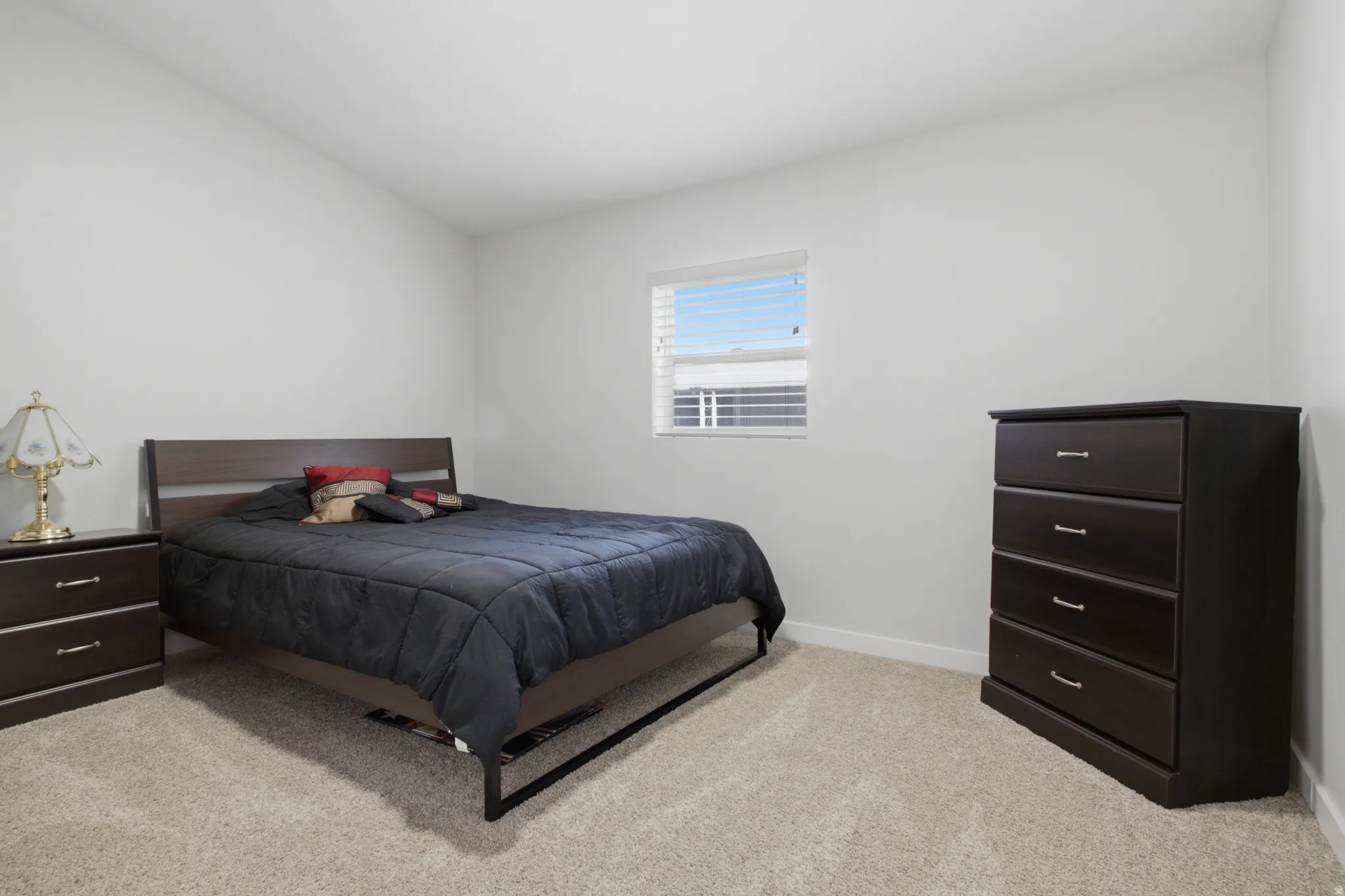 Neutral wall paint, light-colored carpeting, and a window with horizontal blinds