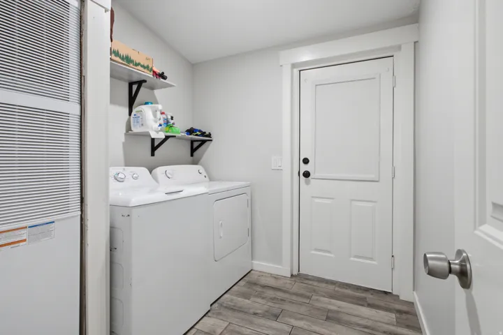 Wood-finish flooring, white walls, and a white paneled door with black hardware