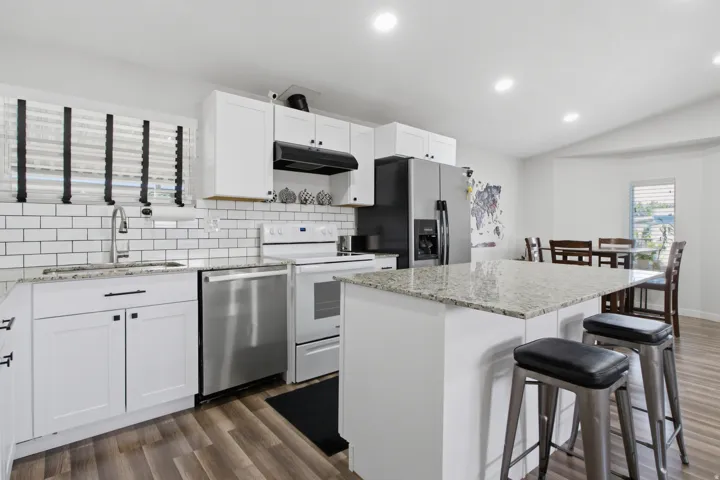 White cabinetry with black hardware, stainless steel appliances, and a subway tile backsplash